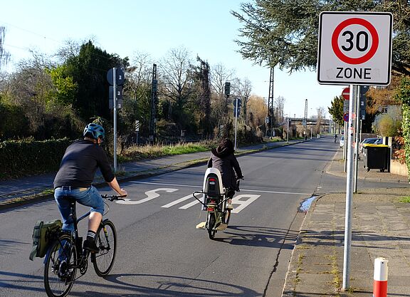Infrastruktur_NRW_Bonn_ADFC_NRW__30 Zwei Radfahrer fahren an einem Tempo 30 Schild vorbei.