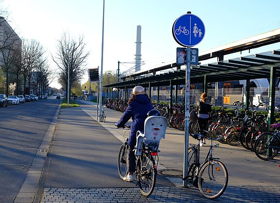 Infrastruktur_NRW_Bonn_ADFC_NRW__17_.JPG Bahnhalt, Regionalbahn, Radabstellanlage und eine Radfahrerin.