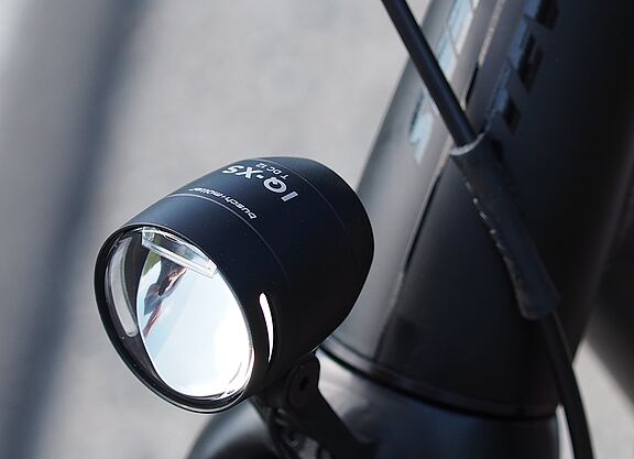 LED-Fahrradscheinwerfer Schwarzer LED-Fahrradscheinwerfer am silbernen Fahrradlenker montiert.